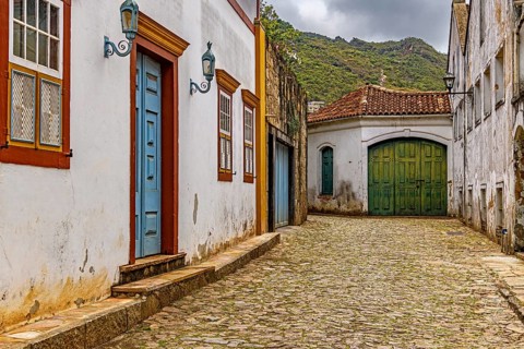 Alley with old colonial-style houses and sunlit cobblestones in the historic city of Ouro Preto in