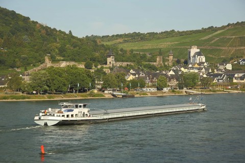 Cityscape with city fortifications and towers of Oberwesel on the Rhine with cargo ship,