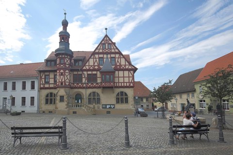 Historic town hall built in 1639, couple sitting on park bench, market square, half-timbered house,