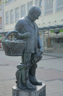 Pretzel Adam sculpture by Werner Bernd 1977, modern art, life-size man standing with basket and