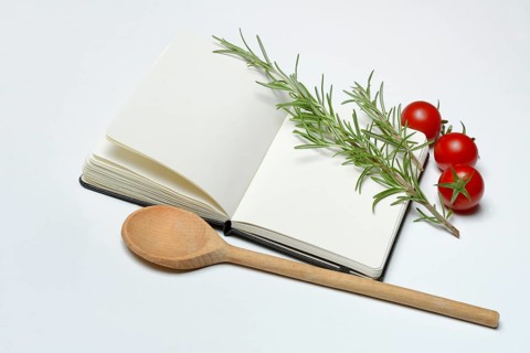 Blank notebook for cooking recipes, cooking spoon with rosemary sprig, tomato