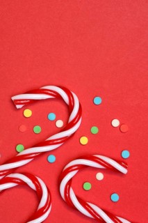 Candy canes and sugar confetti against red background, Christmas