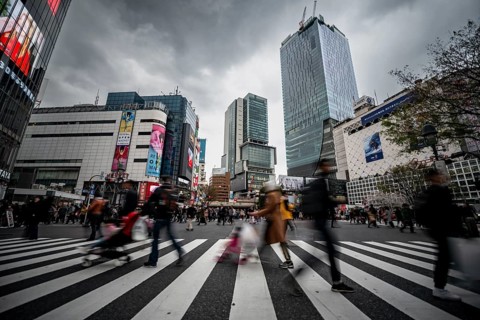 Crowd crossing zebra crossing on a large intersection, motion blur, back modern houses with
