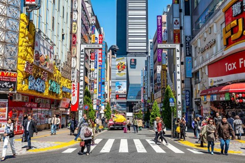 Bustling street scene in Japan with modern buildings and colorful billboards, figure of Godzilla