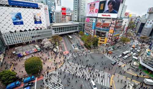 Modern houses with colorful neon signs and large road intersection, Shibuya Crossing from above,