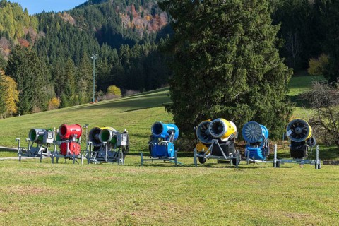 Different snow cannons on an extensive meadow in front of a forest in autumn, Schwangau near