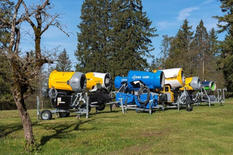 Row of snow cannons in a meadow with trees and partly cloudy sky, Schwangau near Füssen, Ostallgäu,