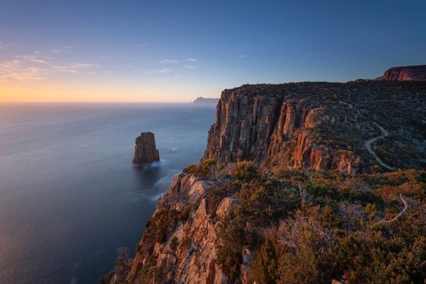 Long exposure at sunrise shows glowing dawn over the dramatic cliffs of Cape Hauy. View towards