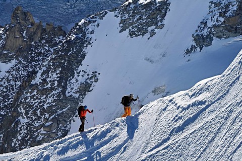 Two mountaineers run across a snow-covered mountain ridge, Aiguille du Midi, Chamonix-Mont-Blanc,