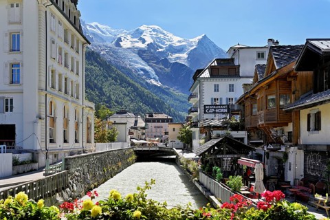 Glacier river Arve flows through the city, with the snow-capped Mont-Blanc mountain range behind,