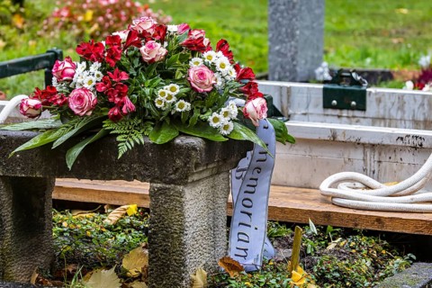 Open grave with a funeral wreath just in front of the burial of a deceased person. Pragfriedhof