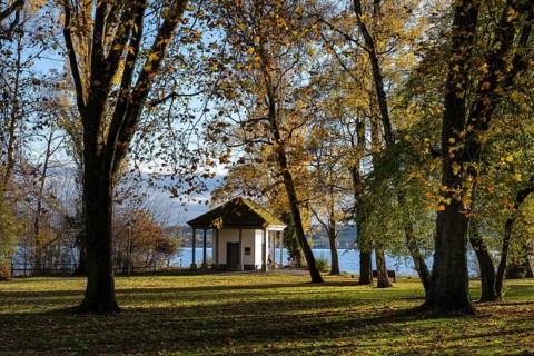 The Mettnaupark, surrounded by autumn vegetation, with the certificate house on the banks of Lake