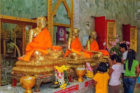 Buddhist believers Buddhists pray making offerings to statues of Buddhist monks covered with gold