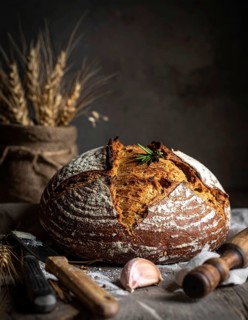 Rustic loaf of whole grain bread, fresh baked, close up of bread on dark wooden table, golden rust,