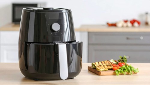 Air fryer with grilled vegetables, wooden table in the kitchen, healthy eating, healthy vegetarian
