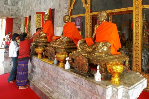 Buddhist believers Buddhists pray making offerings to statues of Buddhist monks covered with gold
