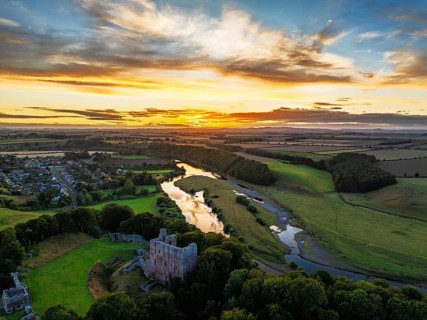 Sunset over Norham Castle and River Tweed from a drone, Norham, Northumberland, England, United