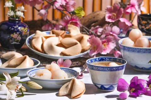 Lychee, lychee wine and fortune cookies in Asian tableware surrounded by blossoms
