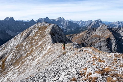 Hikers on the summit ridge of the Gamsjoch, behind rock faces of the Laliderer Spitze, eastern