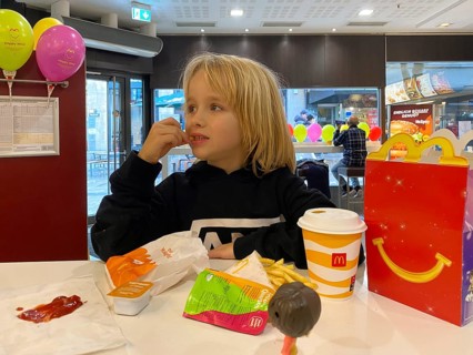 Interior view, child, boy, 7 years, blonde, eating Happy Meal, children's menu, at McDonald's