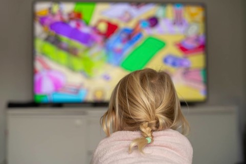 Child, girl, 4 years old, blonde, lying on sofa, watching TV, watching television, in front of
