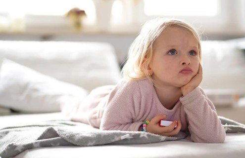 Child, girl, 4 years, blonde, lying on sofa, watching TV, watching television, watching television,