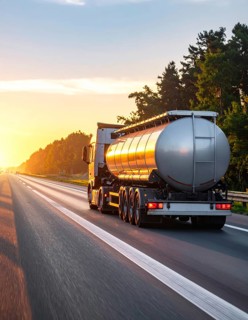 Petrol cargo truck lorry tanker driving on highway hauling oil products at sunrise, wide hilly
