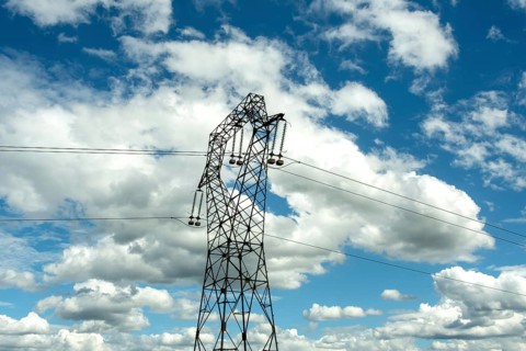 High voltage power lines against a bright blue sky with scattered clouds, Puy de Dome, Auvergne