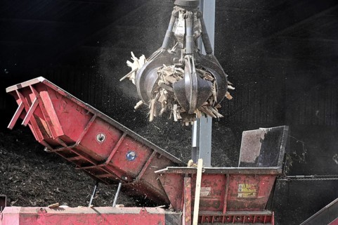 Loading crane with grab arm for loading wood waste for wood pellet production on the premises of