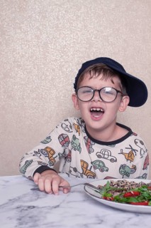 Child reacts dramatically to a salad served on a marble table at home during lunchtime, A little