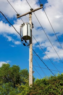 Electricity transformer, high voltage transmission wires, internet, telephone cables attached to