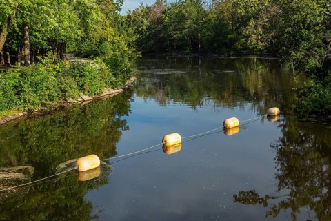 String of yellow cautionary navigation marker buoys on water surafce of river serving to warn,