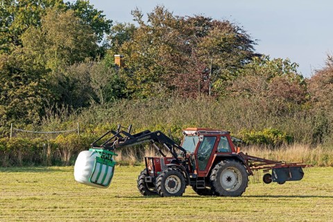 Tractor transporting bales of silage wrapped in film, Falshöft, Pommerby, Schleswig-Holstein,