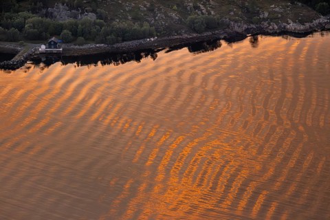Warm sunlight reflects on gentle waves in a bay at sunset, forming a wave-like pattern, Otroya or