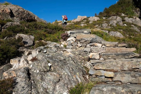 Woman with rucksack climbing the Rørsethornet stone staircase, with 3292 steps one of the longest