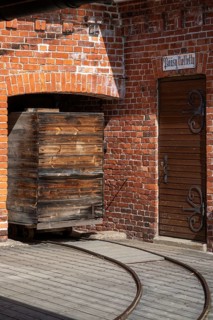 Old wooden trolley on rails, brick wall, former paper mill for the production of groundwood pulp