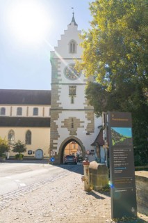 Historic town gate with church tower in the sunshine on an autumnal street, Überlingen, Lake