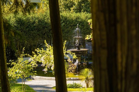 A bubbling fountain in a green garden, surrounded by trees and sunshine, Überlingen, Lake