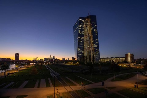 The lights of the European Central Bank (ECB) and the Frankfurt banking skyline glow in the