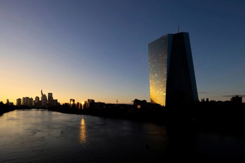 The light of the setting sun is reflected in the glass façade of the Frankfurt banking skyline,