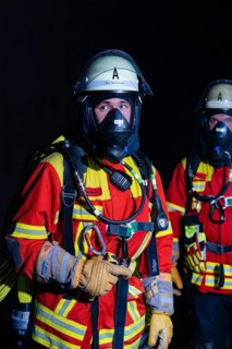 Firefighter with breathing apparatus in the dark, concentrated and ready for action, firefighting