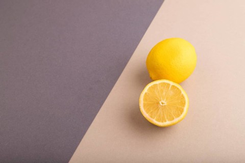 Yellow Lemon Cut in half on beige and gray pastel paper background. Side view, copy space. healthy