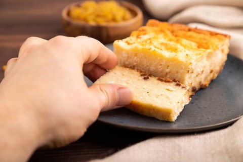 ?ottage cheese ?asserole, Curd cake, with dried apricots and raisins with hand on brown wooden