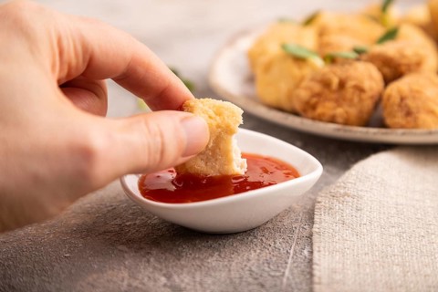 Fried crispy Chicken Nuggets with ketchup, microgreen on brown concrete background and linen