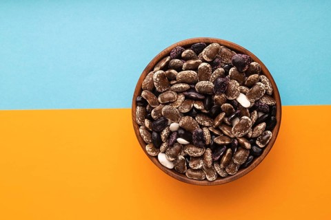 Wooden bowl with Kidney beans on blue and orange pastel paper background, top view, flat lay, copy