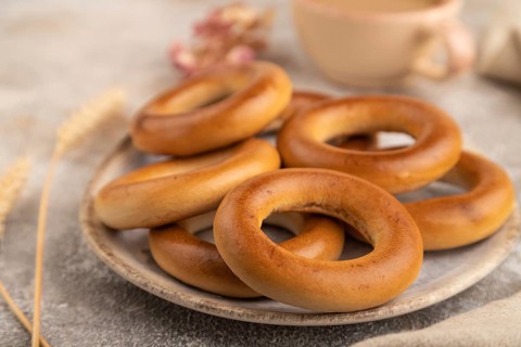 Homemade Ring Bagel with cup of coffee on brown concrete background and linen textile. side view,