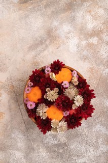 Wooden bowl with carrot slices and red Chrysanthemum flowers, Astrantia flowers, flower salad on