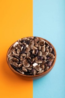 Wooden bowl with Kidney beans on blue and orange pastel paper background, side view, copy space,