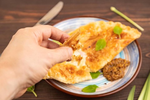 Fried homemade Khachapuri cake with cheese and meat, fried in pan with hand. Traditional Georgian