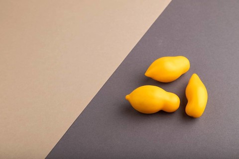 Yellow tomatoes on beige and gray pastel paper background. Side view, copy space. healthy food,